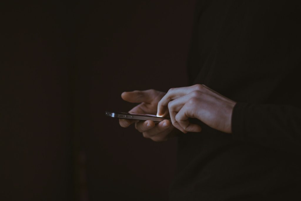 person holding a smart phone in the dark - featured image