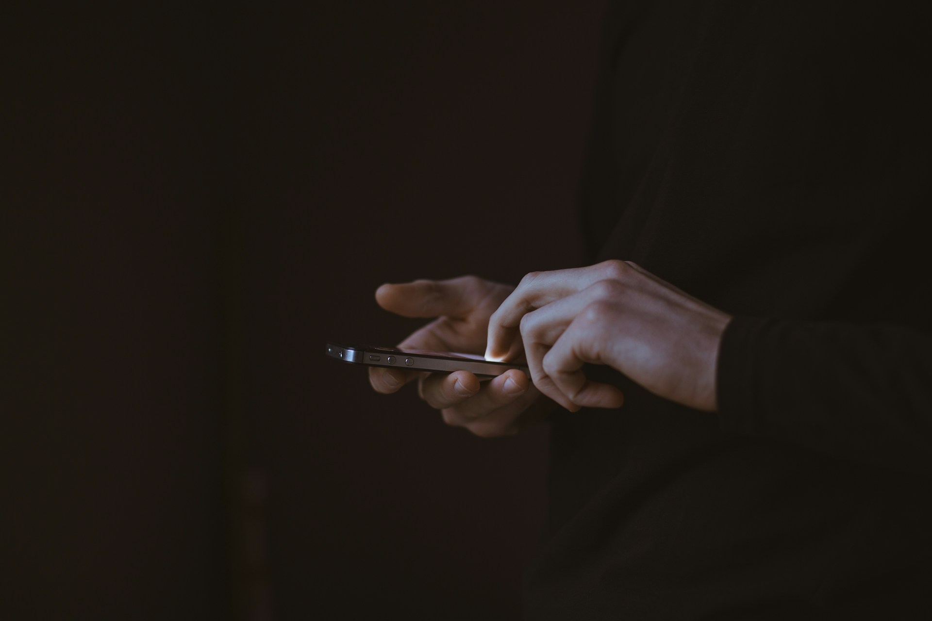 person holding a smart phone in the dark - featured image
